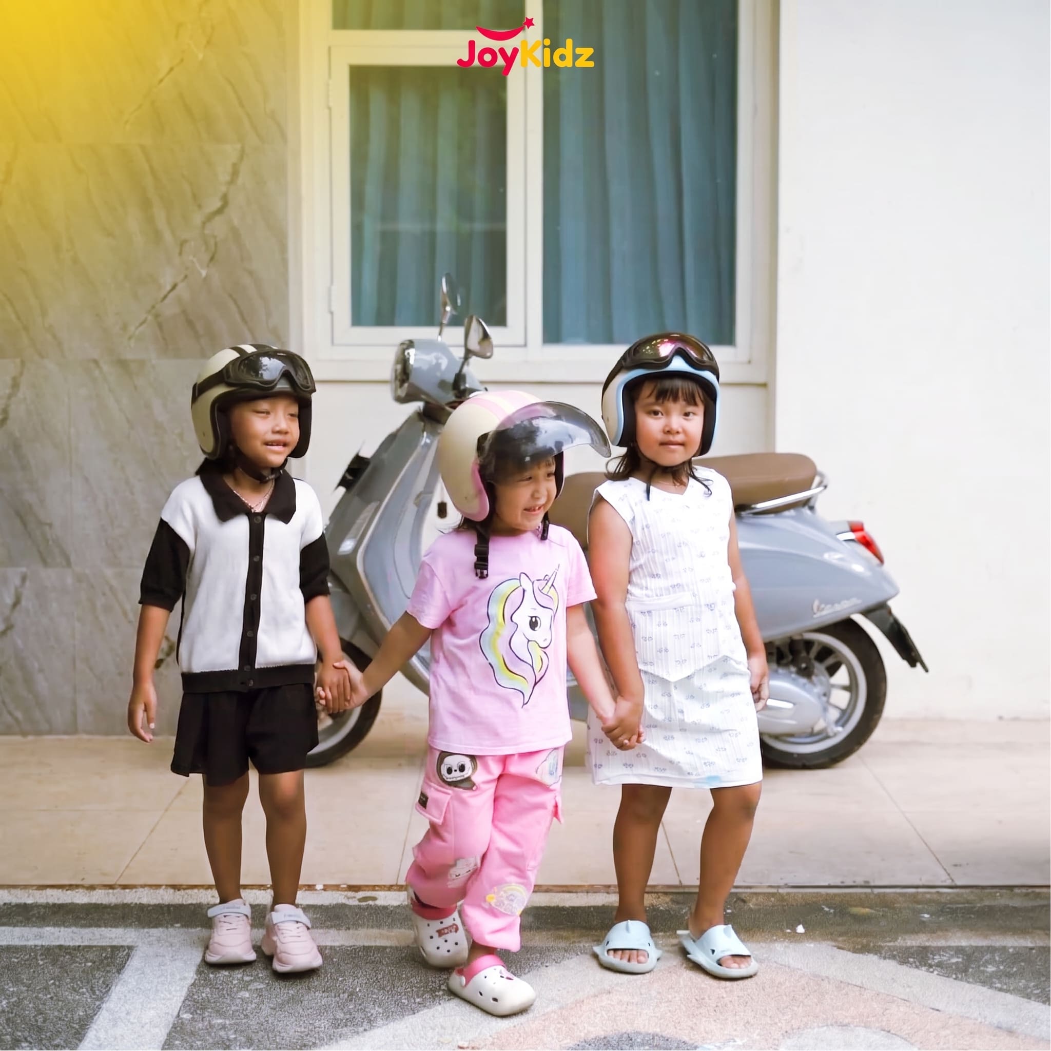 Tiga anak bergandengan tangan, semuanya memakai helm JoyKidz